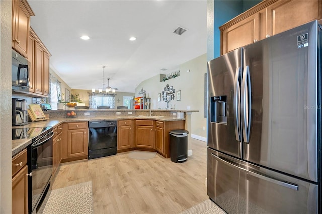 kitchen featuring a peninsula, light wood-style flooring, a sink, visible vents, and black appliances