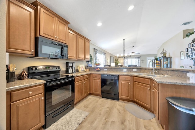 kitchen featuring lofted ceiling, light wood finished floors, visible vents, a sink, and black appliances
