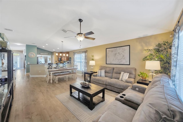 living area featuring lofted ceiling, visible vents, baseboards, and ceiling fan with notable chandelier