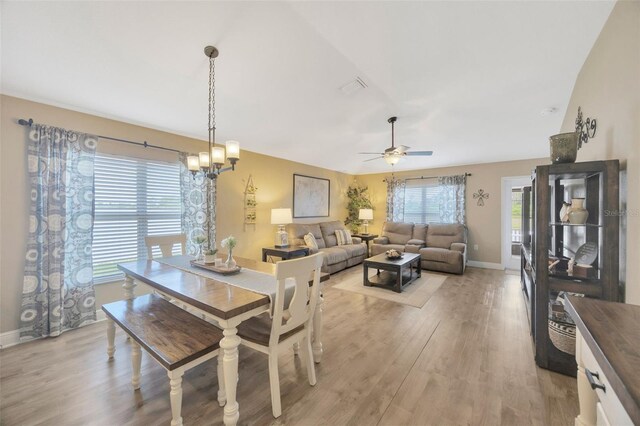 dining room with light wood-type flooring, baseboards, visible vents, and ceiling fan with notable chandelier