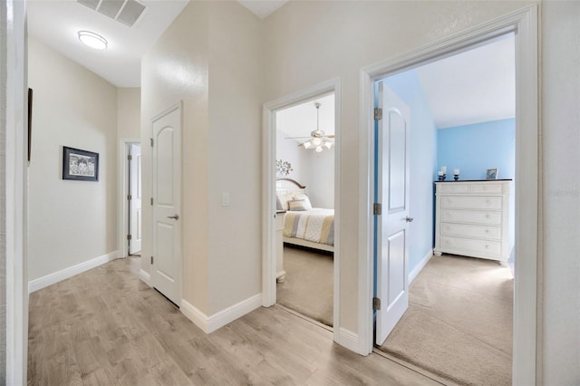 corridor with baseboards, visible vents, and light wood-style flooring