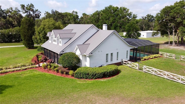 10101 Bryant Rd, Lithia, FL 33547 - view of side of property featuring an outdoor pool, a chimney, glass enclosure, a metal roof, and view of wooded area