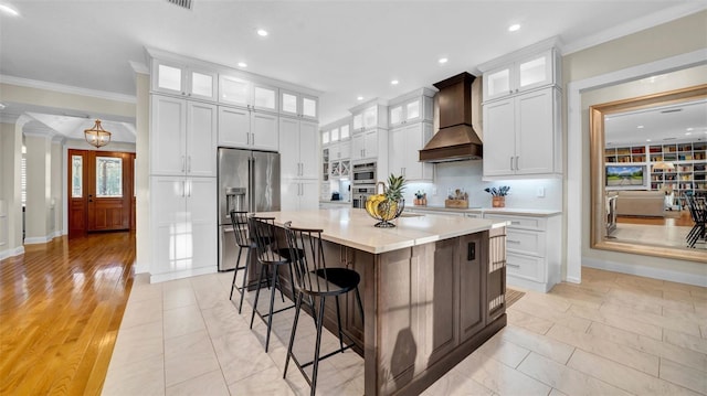 10101 Bryant Rd, Lithia, FL 33547 - kitchen with high quality fridge, custom exhaust hood, ornamental molding, a kitchen island, and light countertops