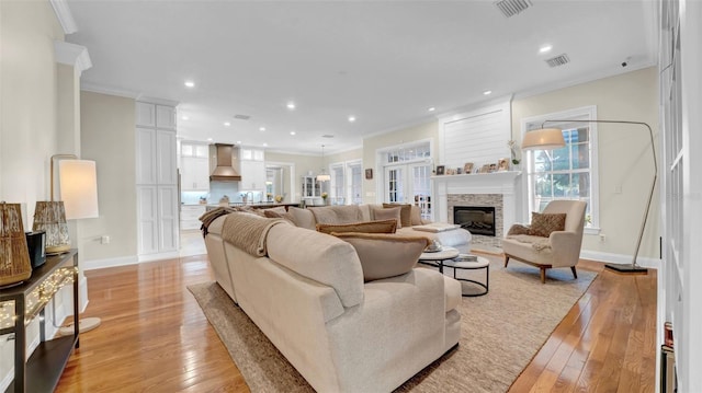 10101 Bryant Rd, Lithia, FL 33547 - living area with crown molding, light wood finished floors, a stone fireplace, and recessed lighting