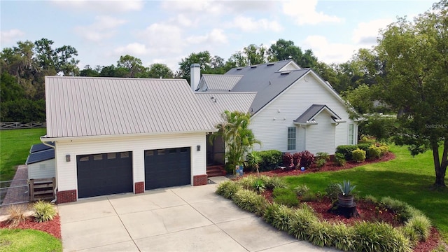 10101 Bryant Rd, Lithia, FL 33547 - modern farmhouse with driveway, brick siding, a chimney, a metal roof, and an attached garage