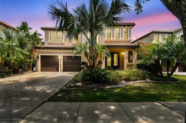 mediterranean / spanish-style home featuring stucco siding, a tile roof, driveway, and an attached garage