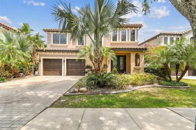 mediterranean / spanish home with a tile roof, driveway, a garage, and stucco siding