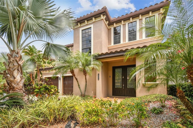 entrance to property featuring a tile roof, stucco siding, and french doors