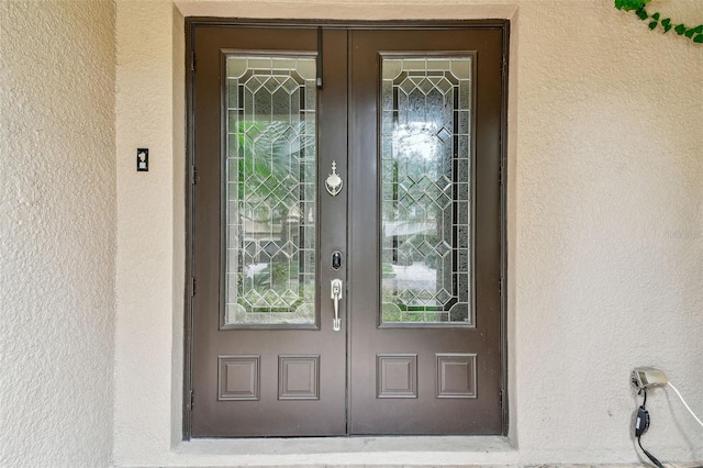 property entrance with stucco siding and french doors