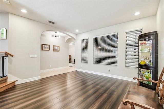 living area featuring recessed lighting, arched walkways, baseboards, visible vents, and dark wood-type flooring