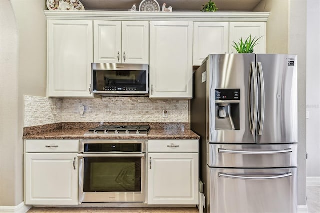 kitchen featuring appliances with stainless steel finishes, baseboards, white cabinets, and backsplash