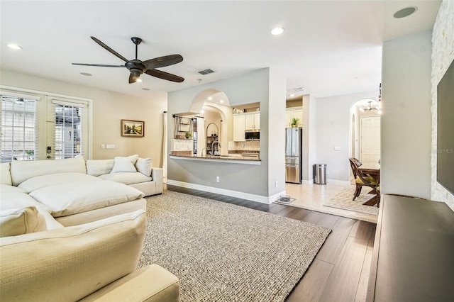 living room with ceiling fan, visible vents, arched walkways, recessed lighting, and wood finished floors