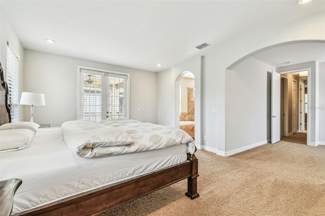 bedroom with visible vents, light carpet, baseboards, arched walkways, and multiple windows