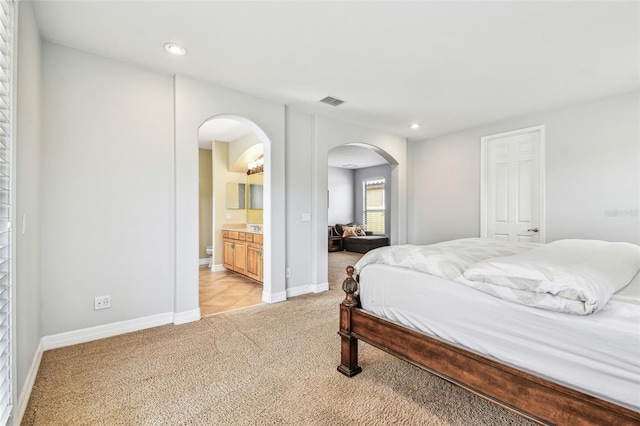 bedroom with recessed lighting, arched walkways, visible vents, and light colored carpet
