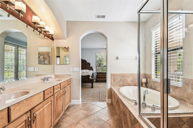 ensuite bathroom with visible vents, connected bathroom, a garden tub, and a sink