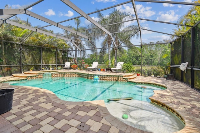 pool with a patio, glass enclosure, and an in ground hot tub
