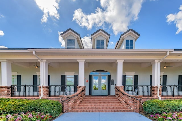 doorway to property with brick siding, a porch, stucco siding, and a ceiling fan