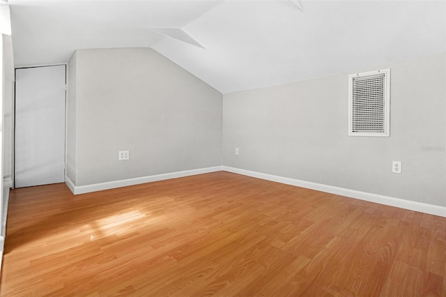 additional living space featuring light wood finished floors, vaulted ceiling, and baseboards