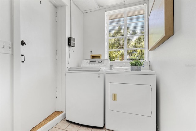washroom with light tile patterned floors, cabinet space, and washer and clothes dryer