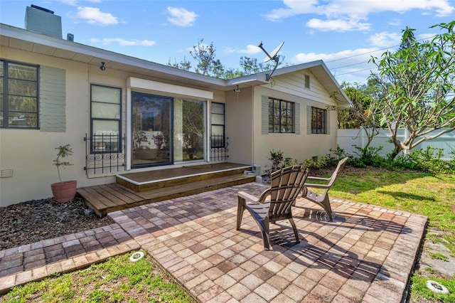 back of house featuring a patio, a chimney, stucco siding, and fence