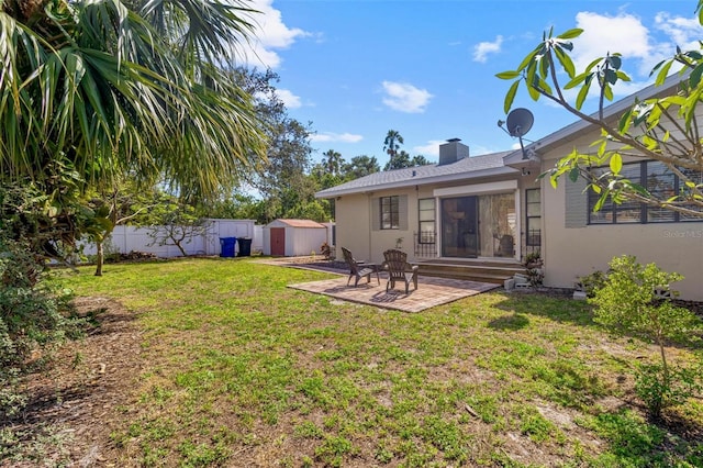rear view of house featuring fence, an outbuilding, a storage shed, a patio area, and a lawn
