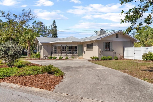ranch-style home with stucco siding, fence, a chimney, and curved driveway