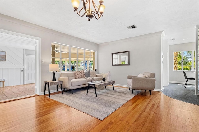 living room featuring an inviting chandelier, visible vents, wood finished floors, and baseboards