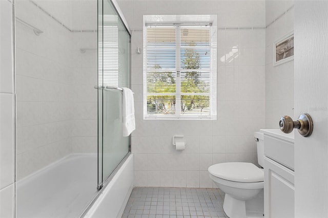 full bath featuring toilet, tile walls, shower / bath combination with glass door, and tile patterned floors