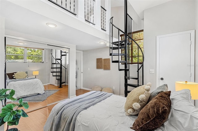bedroom featuring a high ceiling, wood finished floors, and baseboards