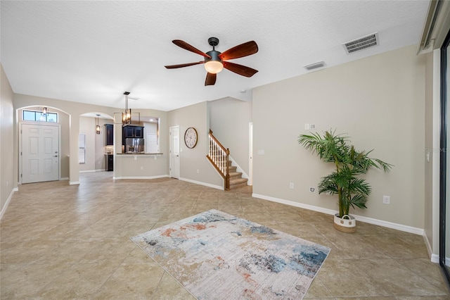 2527 Silverback Ct, Palm Harbor, FL 34684 - unfurnished living room with ceiling fan with notable chandelier, visible vents, arched walkways, and stairway