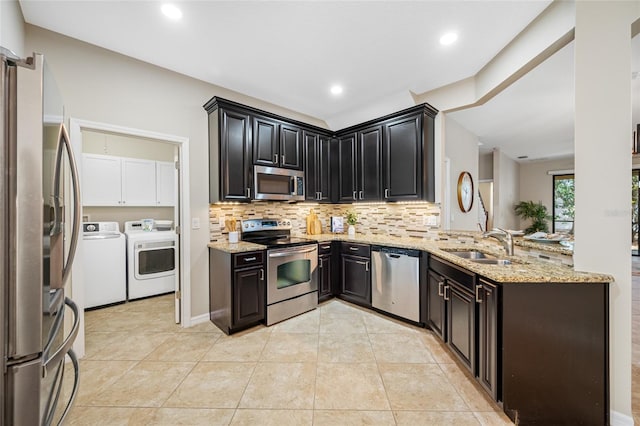 2527 Silverback Ct, Palm Harbor, FL 34684 - kitchen featuring a sink, washer and clothes dryer, backsplash, light stone countertops, and appliances with stainless steel finishes