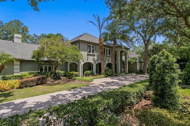 mediterranean / spanish home featuring a chimney, driveway, and stucco siding