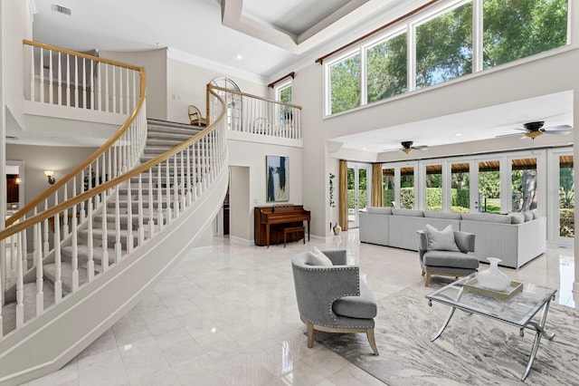 living room with a ceiling fan, marble finish floor, stairs, and a towering ceiling