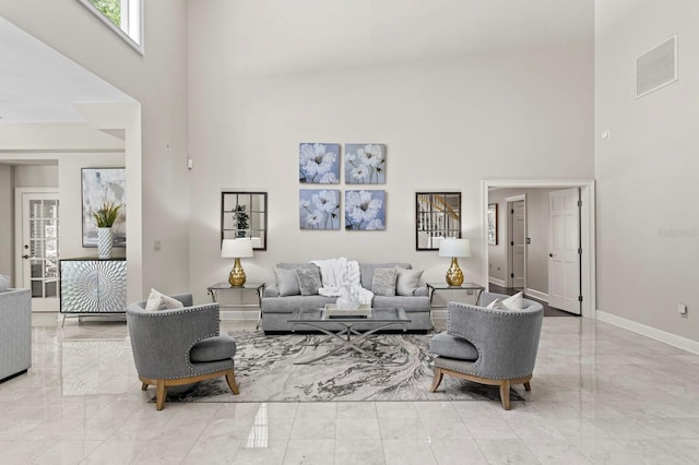 living room featuring visible vents, marble finish floor, and a towering ceiling