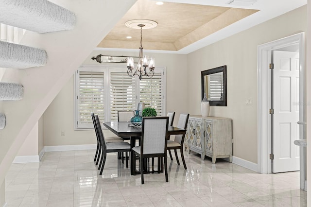 dining room featuring a tray ceiling, marble finish floor, baseboards, and a notable chandelier