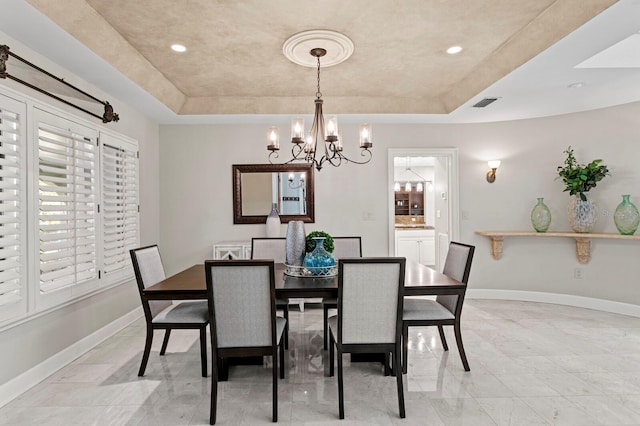 dining space featuring a tray ceiling, a chandelier, and baseboards
