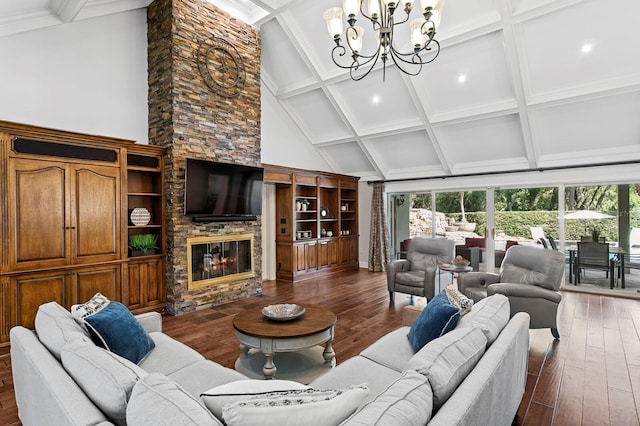 living area with a chandelier, a high ceiling, a stone fireplace, and beam ceiling