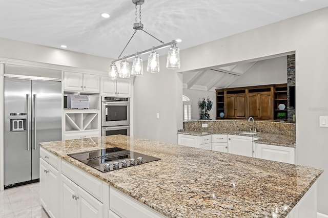 kitchen featuring white cabinetry, light stone counters, appliances with stainless steel finishes, and a sink