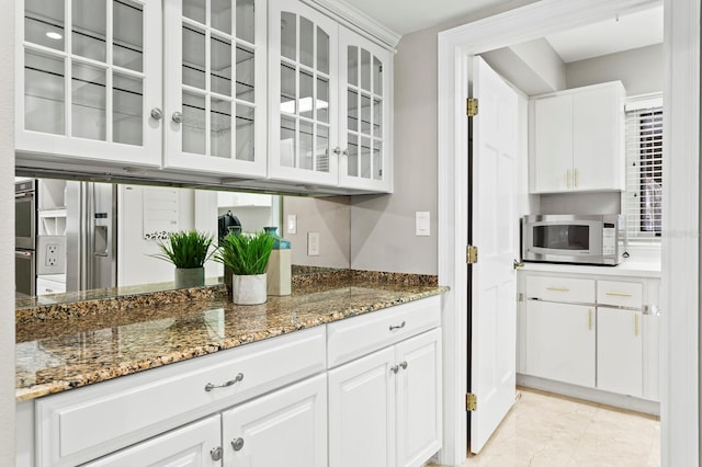 kitchen with stone counters, double oven, white cabinetry, and glass insert cabinets