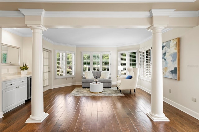 living area featuring baseboards, dark wood finished floors, and ornate columns