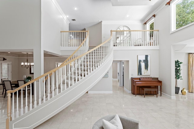 stairs with a chandelier, crown molding, and a high ceiling