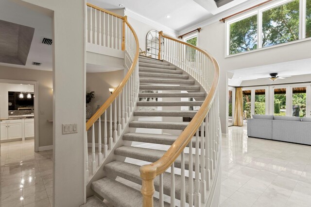 stairway featuring marble finish floor, ornamental molding, a ceiling fan, and visible vents