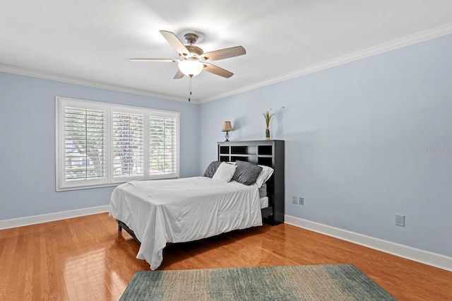 bedroom featuring a ceiling fan, wood finished floors, baseboards, and ornamental molding