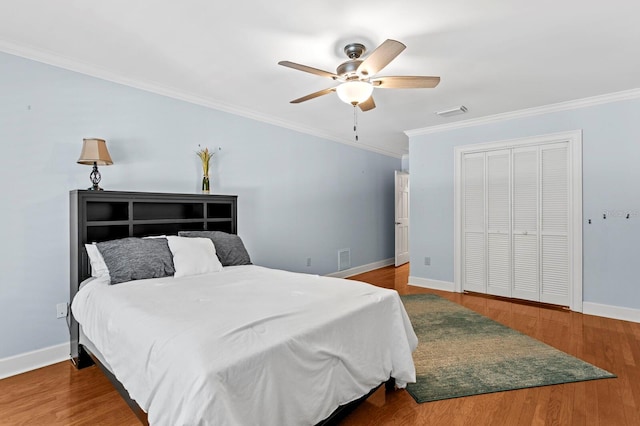 bedroom featuring a closet, wood finished floors, ornamental molding, a ceiling fan, and baseboards
