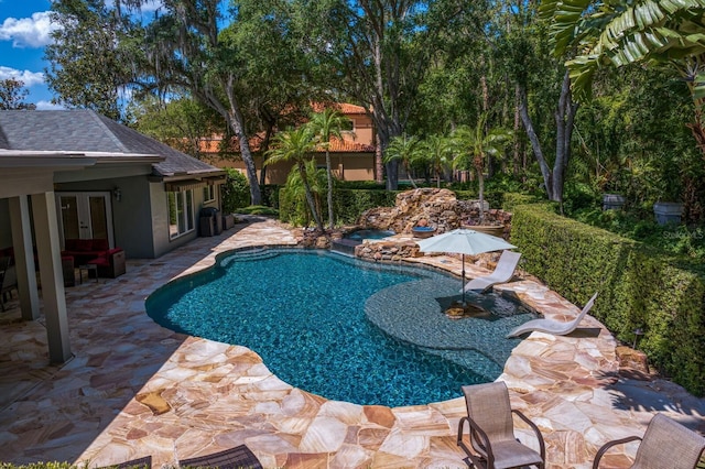 outdoor pool with a patio area, an in ground hot tub, and french doors