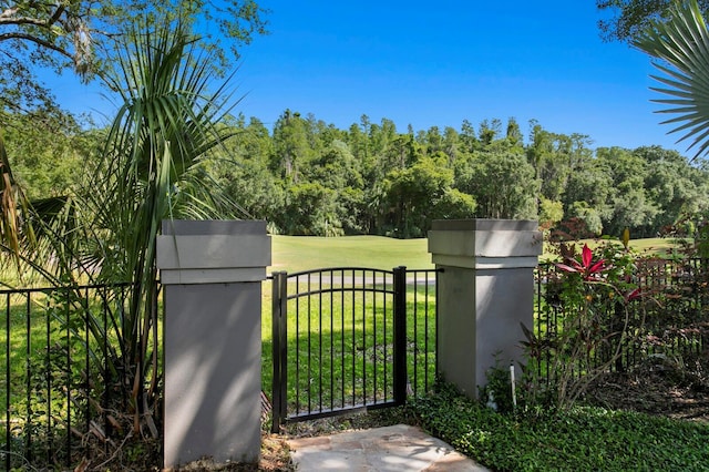 view of gate with fence and a lawn