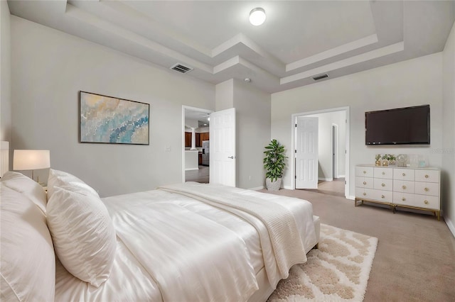 bedroom featuring visible vents, baseboards, a tray ceiling, and light carpet