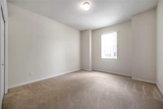 unfurnished room featuring baseboards and light carpet