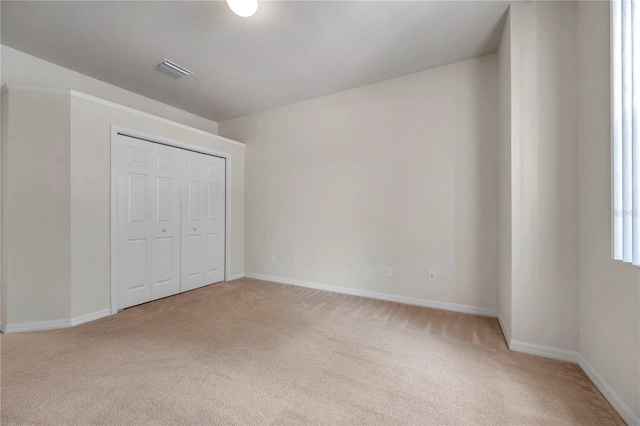 unfurnished bedroom with carpet floors, baseboards, visible vents, and a closet