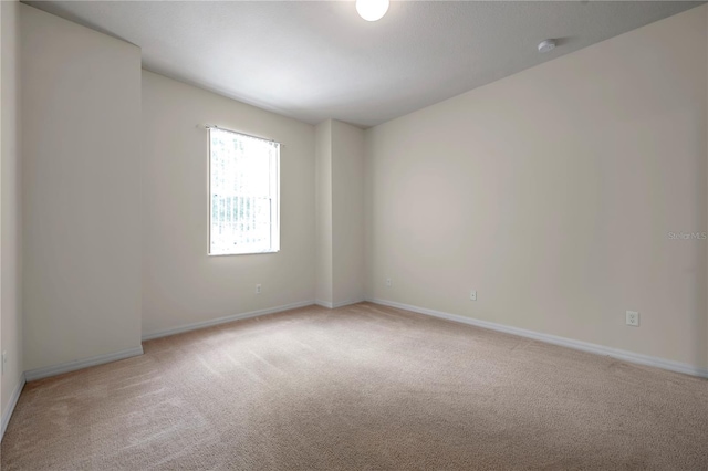 spare room featuring baseboards and light colored carpet